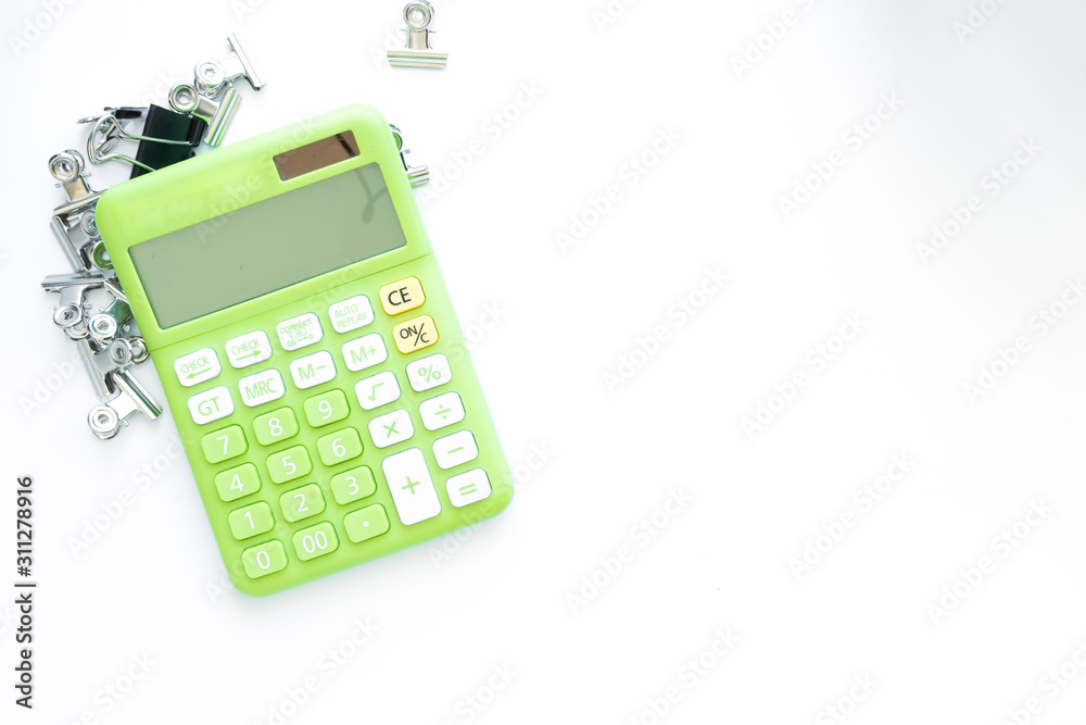 Green calculator and office accessories on white background,with copy space and top view. Green calculator and office accessories on white background,with copy space and top view.