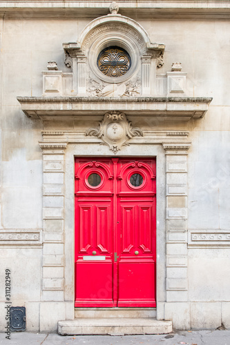 Paris, beautiful red wooden door, typical building in the Marais, with carved lintel