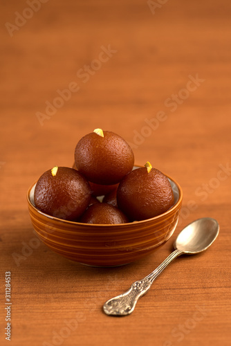 Gulab Jamun in bowl on wooden background. Indian Dessert or Sweet Dish.
