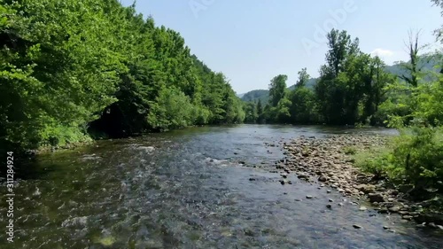 Flying close above a river in Osilnica in Slovenia in nature with lots of green on a beautiful sunny day. photo