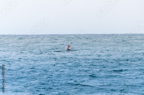 A single kayak-er paddles in the ocean off the coast of Maui Hawaii. Photo taken in a horizontal, landscape orientation 