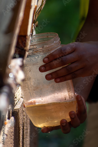 Tableau sur toile African American child holds up glass jars to gather dirty water draining
