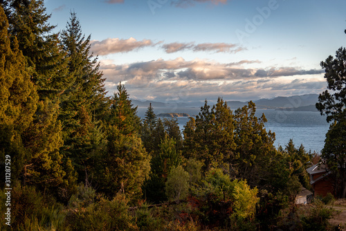 Beautiful cloudy sunset view of the lake Nahuel Huapi, its islands and mountains in the background, surrounded by forests in Bariloche, Argentina