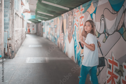 Portrait of young beautiful asian woman was walking along the graffiti wall © Panassak