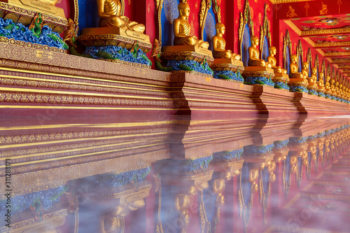 Many meditation Buddha statues are laid in rows on the corridor of Bang Tong Temple. Krabi Province, Thailand