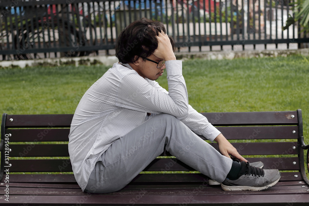 Upset stressed young Asian business man sitting on stairs and suffering from severe depression. Unemployment and layoff concept. Upset stressed young Asian business man sitting on stairs and suffering from severe depression. Unemployment and layoff concept.