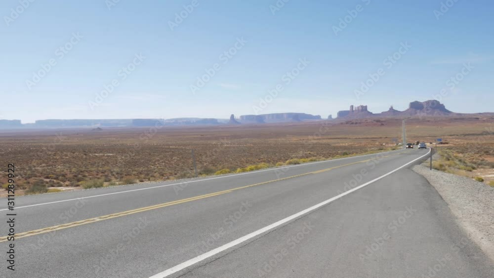 Monument Valley In Arizona, United States Of America - Cars On The Road On A Sunny Day With Scenic Sandstone Formations In The Background - Panoramic Shot Monument Valley In Arizona, United States Of America - Cars On The Road On A Sunny Day With Scenic Sandstone Formations In The Background - Panoramic Shot