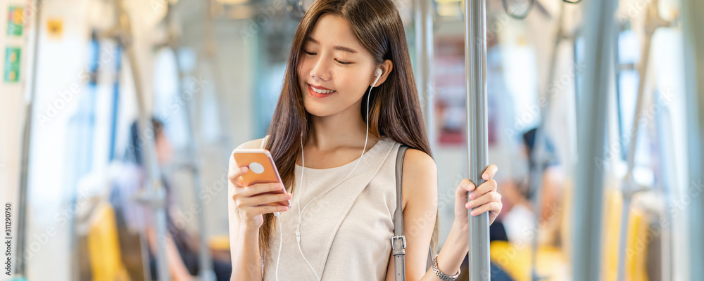 Banner, web page or cover template of Young Asian woman passenger using and listening music via smart mobile phone in subway train station, japanese,chinese,Korean lifestyle, leisure and daily life,