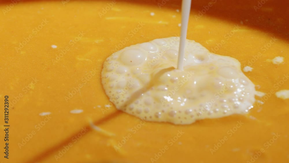 Pouring cream into tomato soup Pouring cream into tomato soup