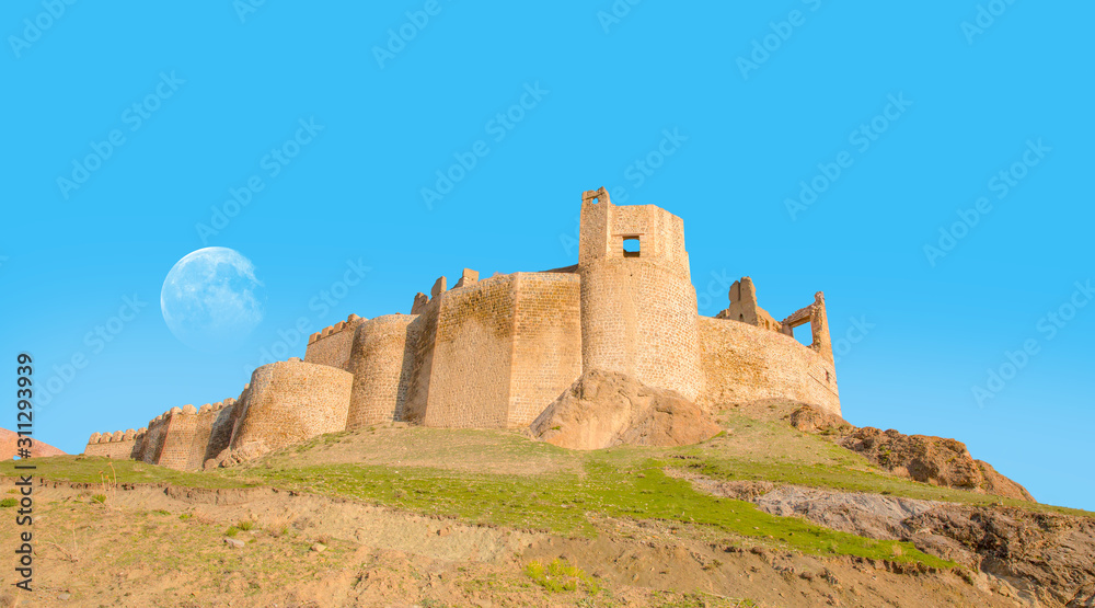 Hosap Castle with bright blue sky with full moon - Van, Turkey 