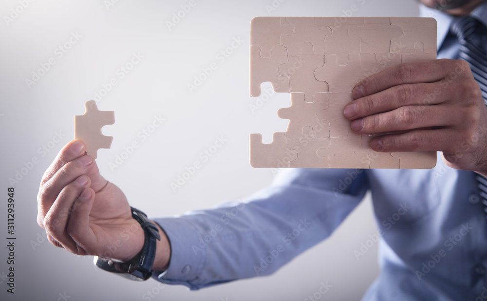 Fototapeta premium Businessman assembling jigsaw puzzle. Business