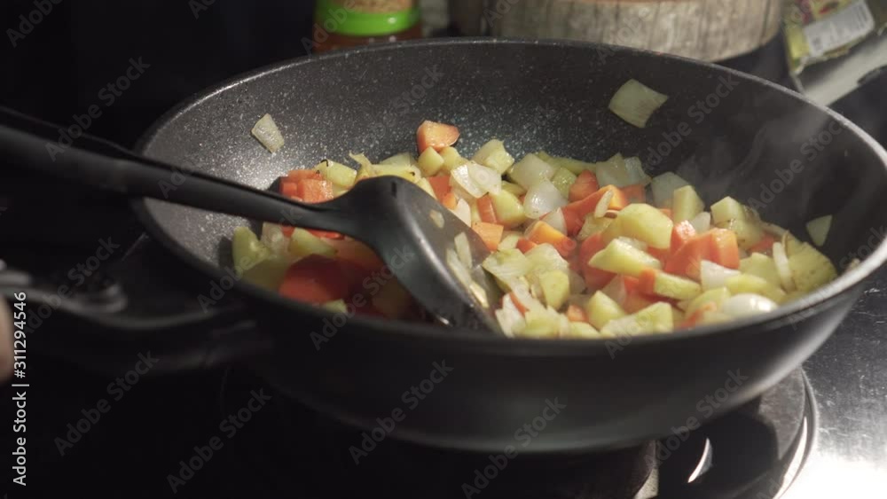 Chef frying vegetables in a pan and then finish it. carrot, potato, onion on a pan. Chef frying vegetables in a pan and then finish it. carrot, potato, onion on a pan.