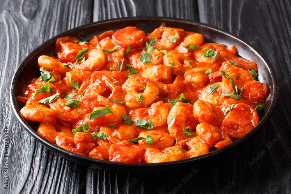 Tasty prawns fried with garlic and spices in tomato sauce close-up in a plate. horizontal Tasty prawns fried with garlic and spices in tomato sauce close-up in a plate. horizontal