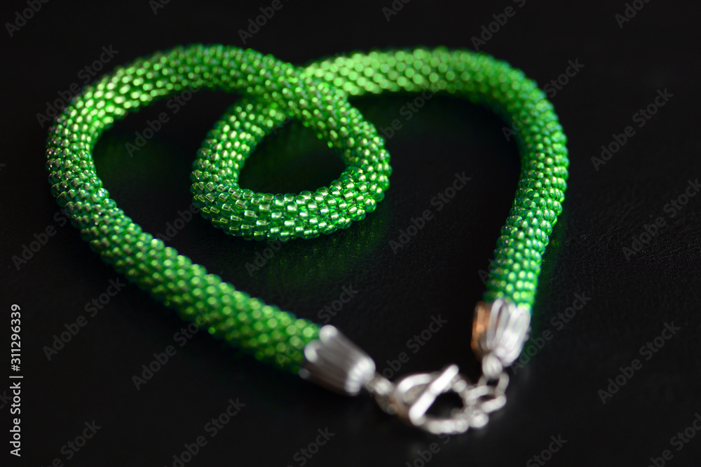 Light green beaded necklace on a dark surface close-up. Fashion background