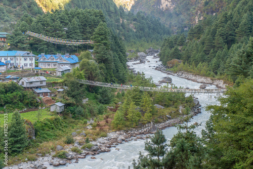 Group of trekker walking on hanging bridge for crossing Dudh Kosi river nearly Phakding village (2600 metres) the main stopping point for trekkers on their way to Everest base camp, Nepal. photo