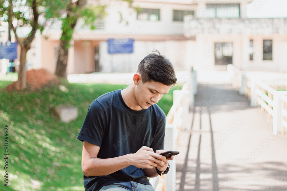 Asian Man Using Smart Phone At park Asian Man Using Smart Phone At park