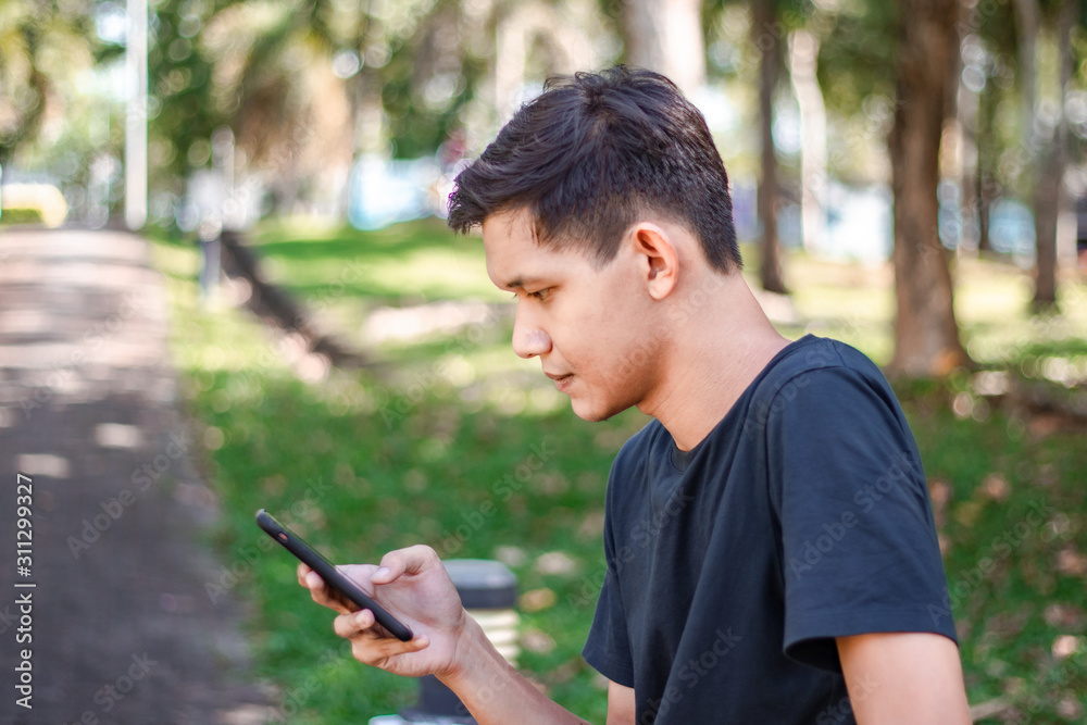 Asian Man Using Smart Phone At park 