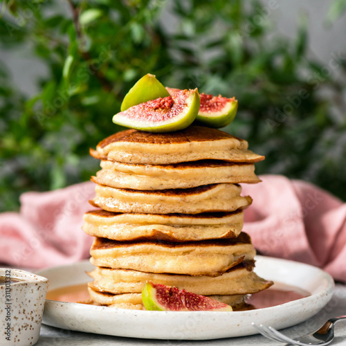 Stack of delicious fluffy pancakes topped with fresh figs and maple syrup. Square orientation. Sweet breakfat food, rich in carbs and gluten photo