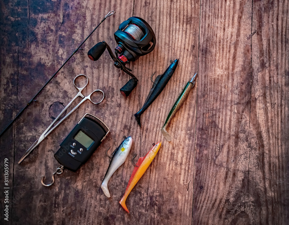 Flat lay of bass lure fishing tackle on a plain wooden background Flat lay of bass lure fishing tackle on a plain wooden background