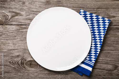 White ceramic tray on a wooden table with a Bavarian napkin, top view. Food background