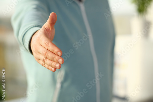 Man in suit and tie give hand as hello in office closeup