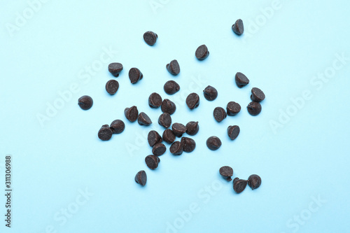 Delicious dark chocolate chips on light blue background, top view
