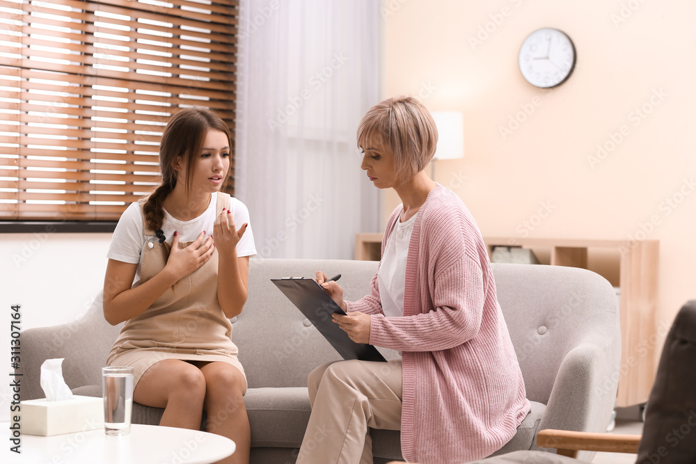 Psychotherapist working with teenage girl in office