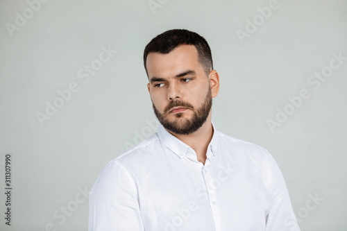 portrait of sad bearded man in white shirt on gray background