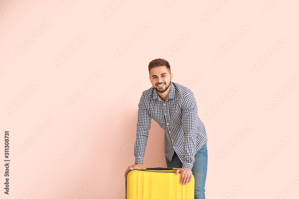 Young man with luggage on color background Young man with luggage on color background