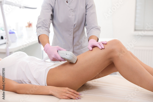 Young woman undergoing laser epilation procedure in beauty salon, closeup