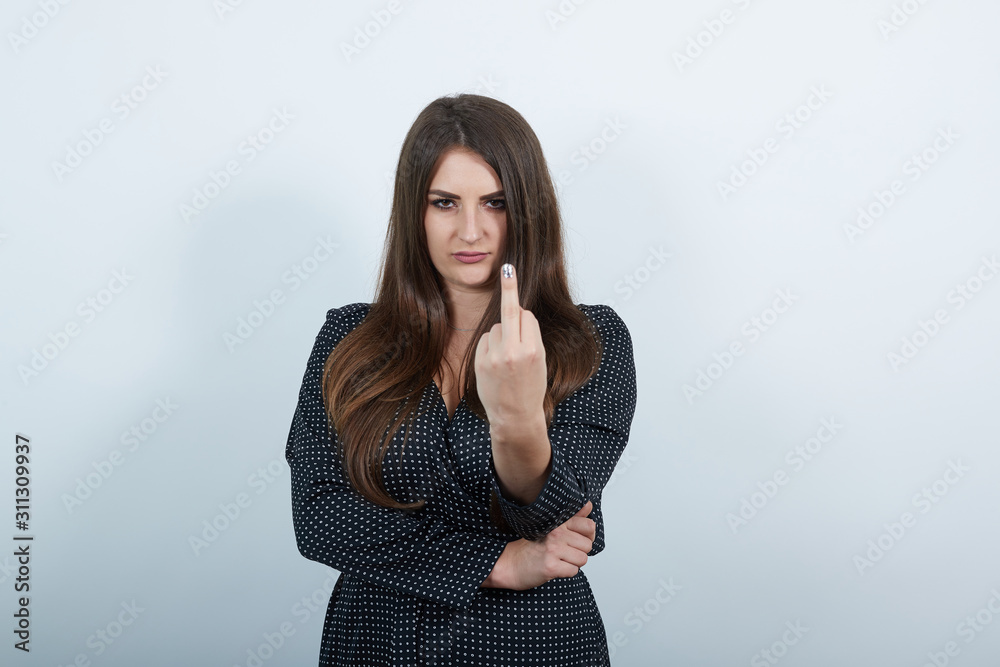 Agressive caucasian woman over isolated gray background wearing casual black dress with white polka dot, showing middle finger at camera. People lifestyle concepte. Agressive caucasian woman over isolated gray background wearing casual black dress with white polka dot, showing middle finger at camera. People lifestyle concepte.