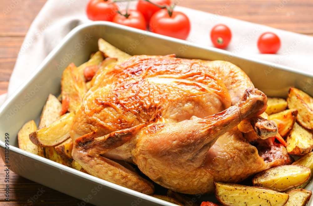 Fototapeta premium Dish with baked chicken and potato on wooden table