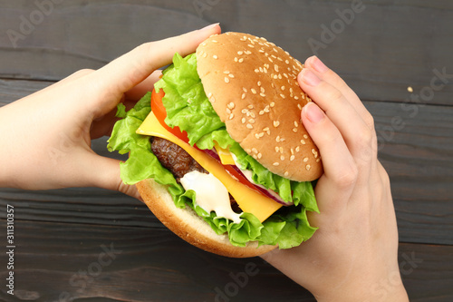 bbq hamburger with vegetables, spices in hands on dark wooden background