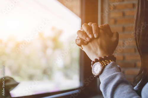 A young woman shows the symbol of prayer to God for the blessings of the Lord to find good things with faith in the sacredness and power of God on the blurred background of nature in the morning.