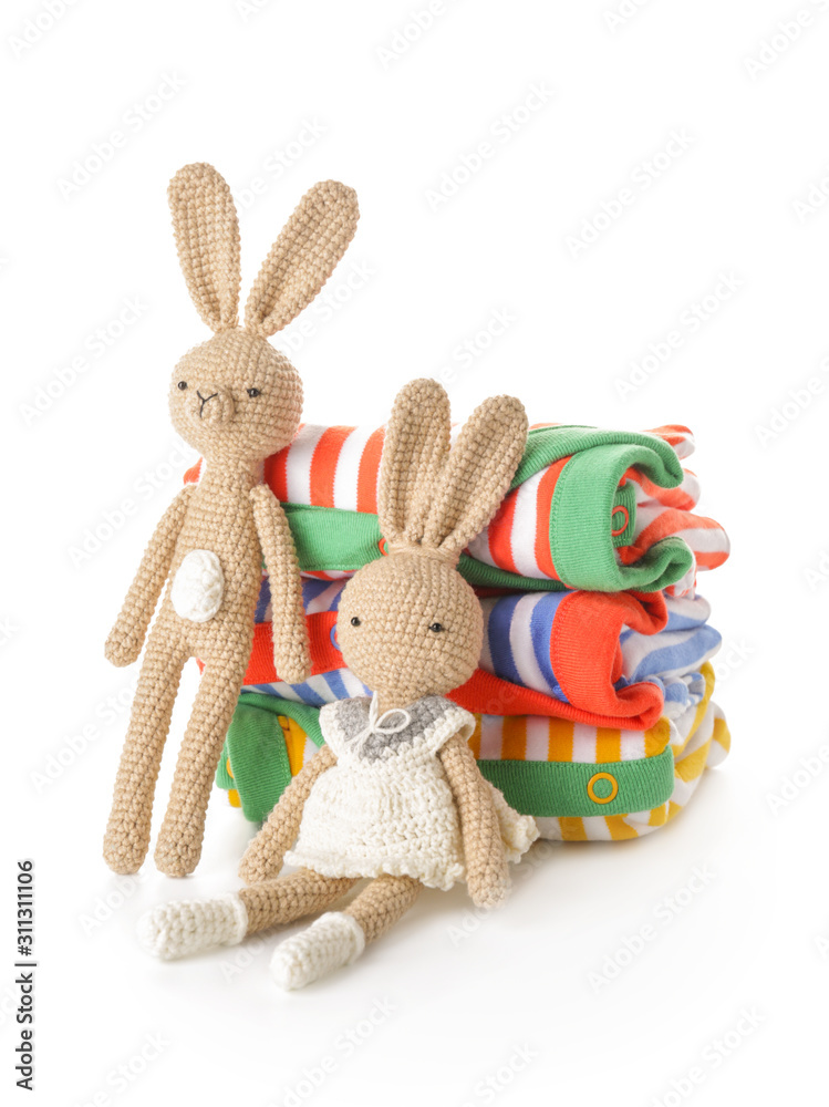 Stack of clean kid clothes with toys on white background