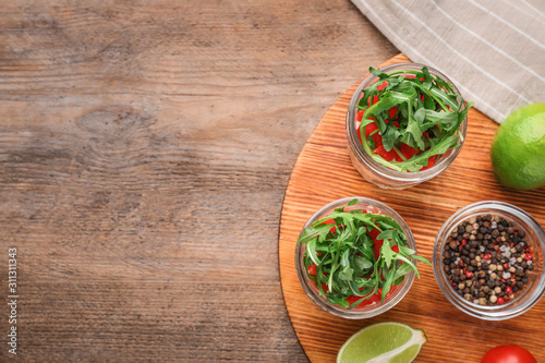 Healthy salad in glass jars on wooden table, flat lay. Space for text