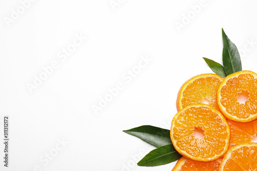 Composition with slices of fresh ripe tangerines and leaves on white background, top view. Citrus fruit