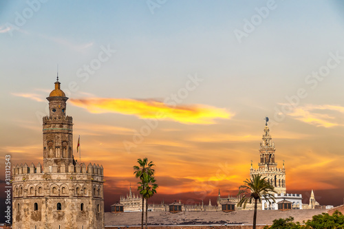 Golden tower (Torre del Oro) and Giralda tower of seville cathedral at sunset from the other side of the Guadalquivir river, Seville (Andalusia), Spain.