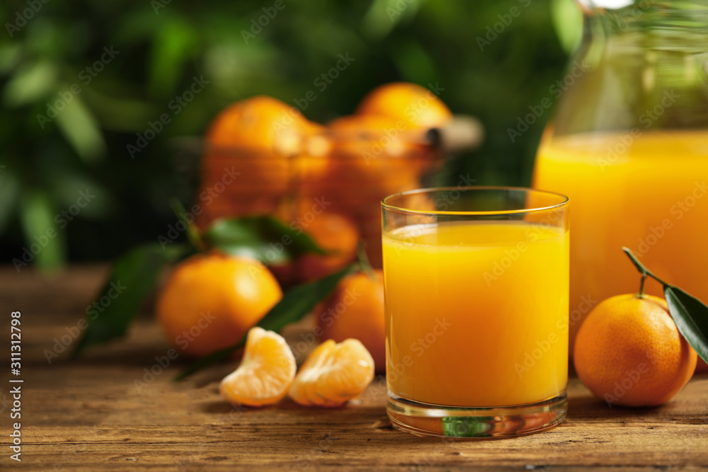 Glass and bottle of fresh tangerine juice and fruits on wooden table Glass and bottle of fresh tangerine juice and fruits on wooden table