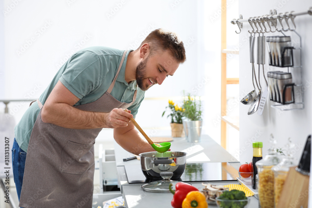 Young man cooking delicious soup in kitchen Young man cooking delicious soup in kitchen