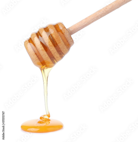 Honey pouring from wooden dipper isolated on white