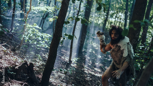 Portrait of Primeval Caveman Wearing Animal Skin and Fur Hunting with a Stone Tipped Spear in the Prehistoric Forest. Prehistoric Neanderthal Hunter Ready to Throw Spear in the Jungle
