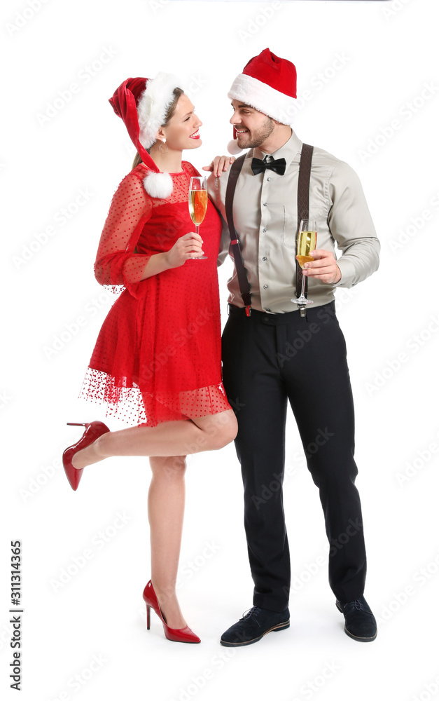 Obraz premium Happy couple in Santa Claus hats and with glasses of champagne on white background