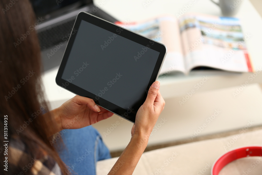female hand holds tablet in home setting while