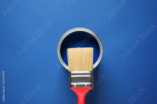 Can of paint and brush on bright background, top view. Color of the year 2020 (Classic blue)