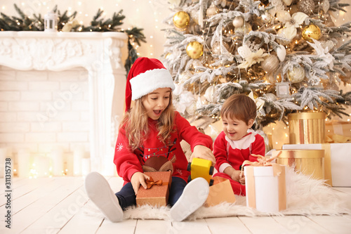 Little children opening Christmas gifts at home