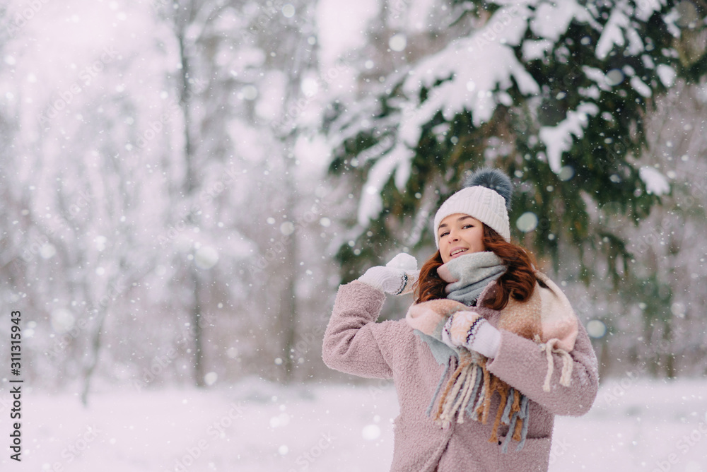 Young joyful woman throws a snow ball while having fun in a winter park Young joyful woman throws a snow ball while having fun in a winter park