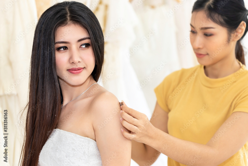 Beautiful Asian lady choosing dress in a shop with tailor assistant. Beautiful Asian lady choosing dress in a shop with tailor assistant.