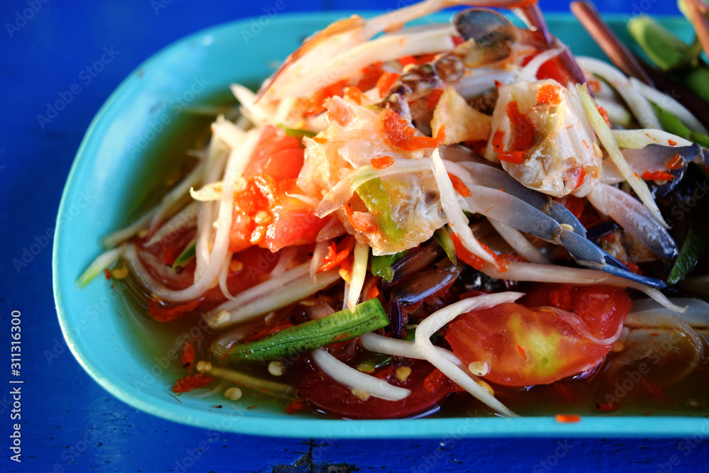 The picture of papaya salad crab in a blue dish is very appetizing with bright light. The picture of papaya salad crab in a blue dish is very appetizing with bright light.