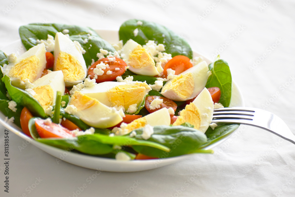 Egg salad with spinach, cherry tomatoes and feta cheese. The concept of healthy food, dietary and weight loss plan. Egg salad with spinach, cherry tomatoes and feta cheese. The concept of healthy food, dietary and weight loss plan.